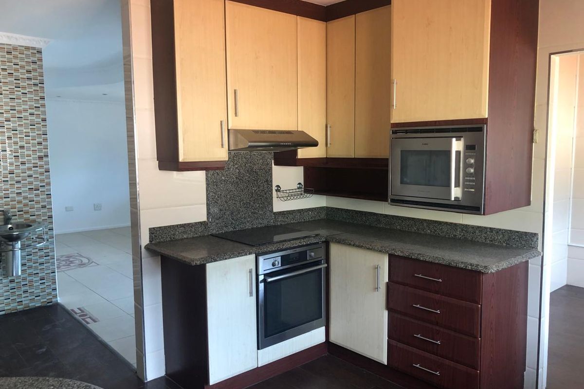 A functional kitchen featuring granite countertops, built-in oven, hob, extractor fan, and integrated microwave with two-tone cabinetry.