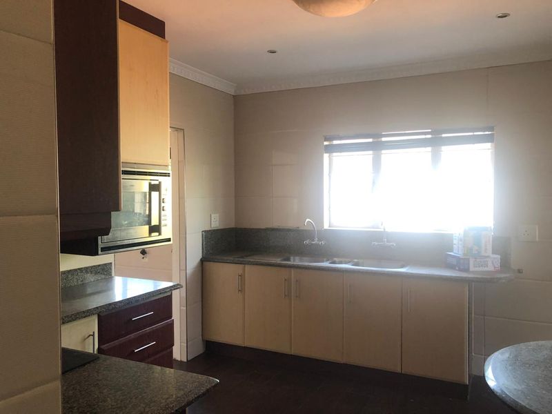 A functional kitchen featuring granite countertops, ample built-in cabinetry, a double basin sink, and a built-in microwave, offering a clean and practical workspace.