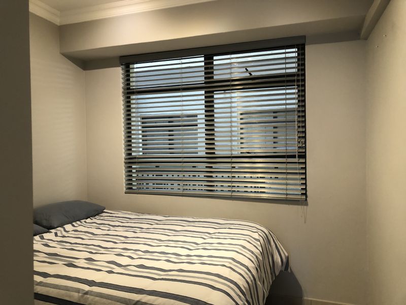 A compact bedroom featuring neutral walls, a window with fitted venetian blinds, and decorative ceiling coving.