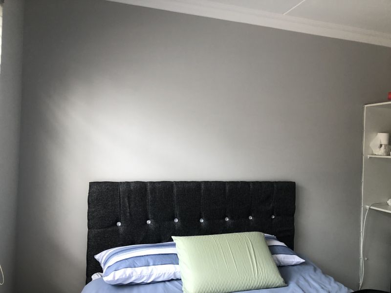 A bedroom featuring neutral grey walls and built-in shelving, providing a clean and functional space.