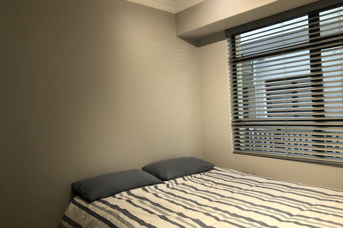 A cozy bedroom featuring neutral wall tones, crown molding, and fitted venetian blinds, providing a clean and functional space.