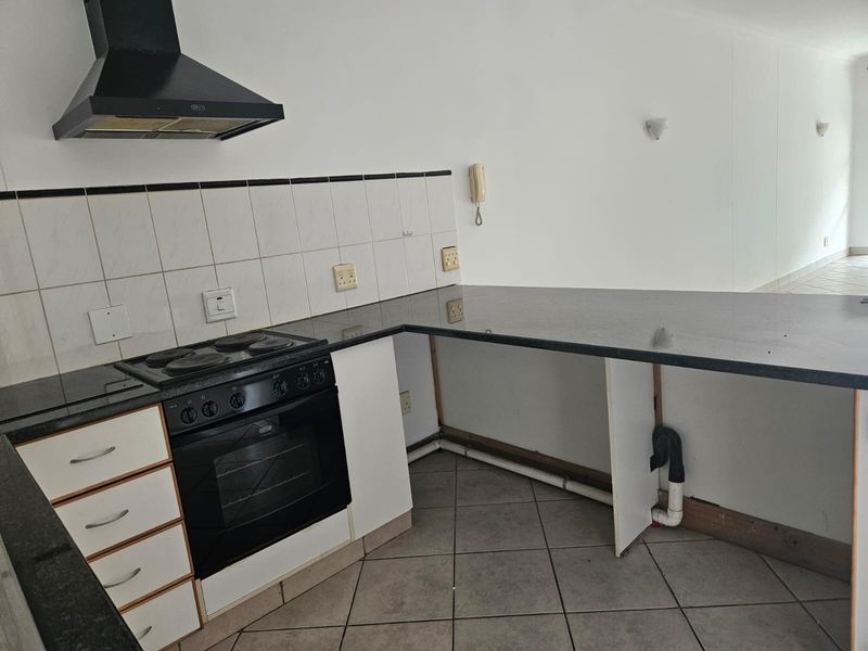 A functional kitchen area featuring granite countertops, a built-in oven with hob, and extractor fan, currently requiring minor cabinetry repairs and finishing.