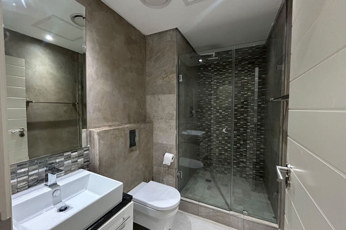 Modern bathroom featuring a glass-enclosed shower with mosaic tiling, a wall-mounted toilet, and a contemporary vessel sink vanity.