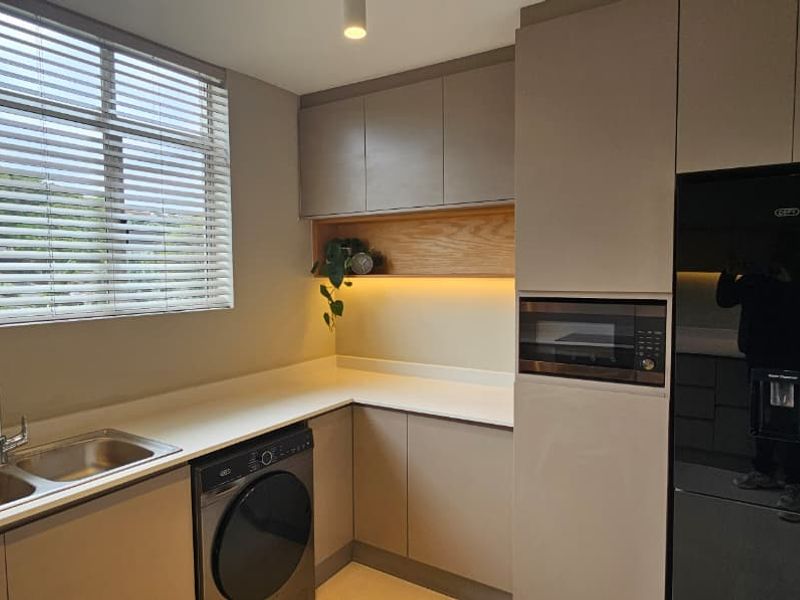 Modern kitchen featuring sleek handleless cabinetry, quartz countertops, integrated microwave, and a double bowl stainless steel sink with contemporary mixer tap.