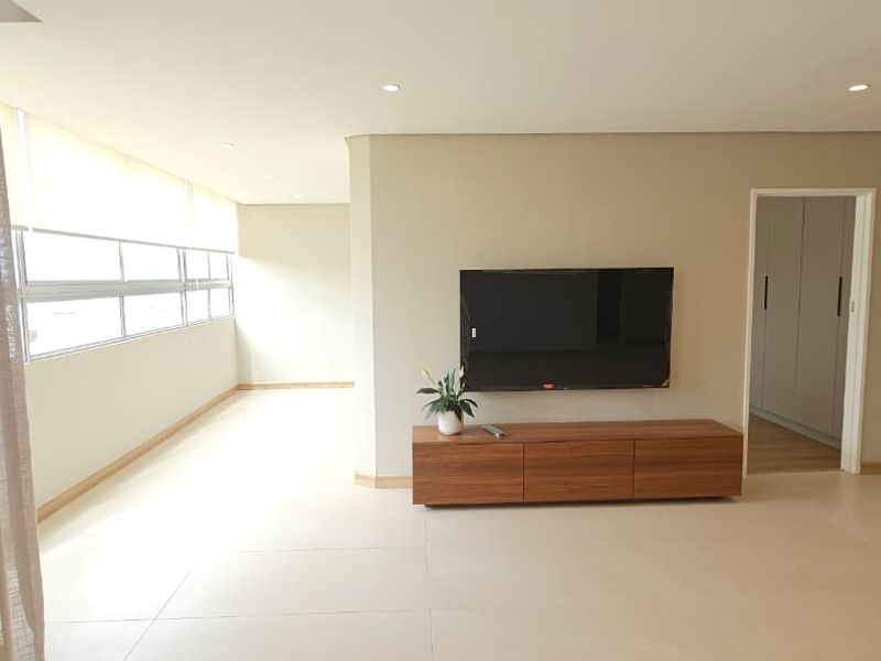 Spacious living area featuring neutral tiled flooring, recessed downlighting, and large windows with roller blinds, offering a bright and clean open-plan layout.
