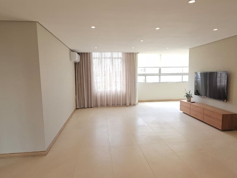 Spacious living area featuring neutral tiled flooring, recessed downlighting, and an integrated air conditioning unit, offering a bright and clean open-plan layout.