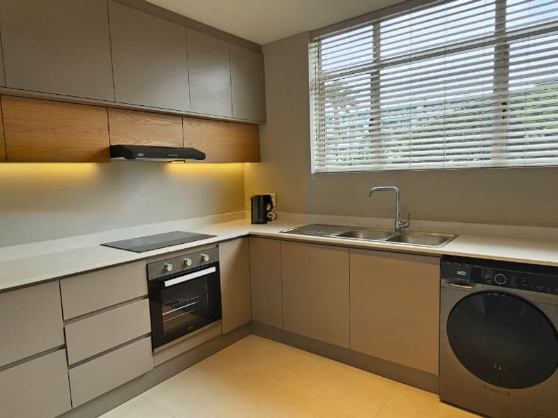 Modern kitchen featuring sleek handleless cabinetry, stone countertops, integrated oven and hob, and under-cabinet lighting, creating a clean and functional workspace.