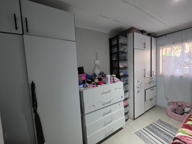 A bedroom featuring built-in cupboards and tiled flooring, requiring some ceiling maintenance and cosmetic updates to improve its overall appeal.