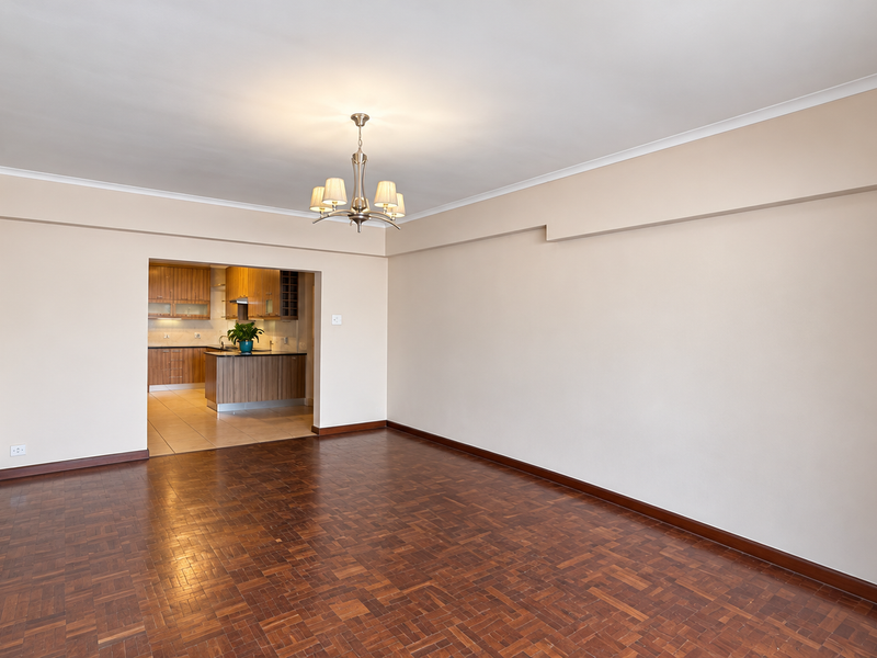 Spacious open-plan living area featuring classic parquet flooring and cove cornicing, seamlessly flowing into a functional kitchen with built-in cabinetry and island.