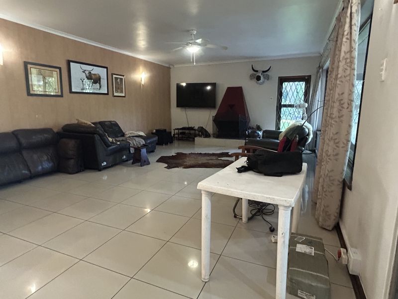 Spacious living room featuring large format floor tiles, a central ceiling fan, and a distinctive freestanding fireplace, offering a comfortable and functional family space.