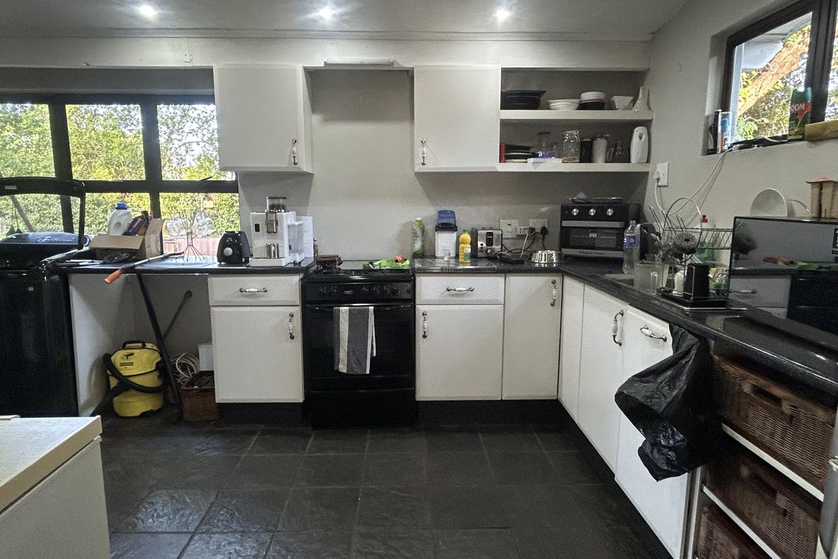 Functional kitchen featuring dark stone countertops, white cabinetry, tiled flooring, and recessed lighting, offering a practical layout with ample storage space.