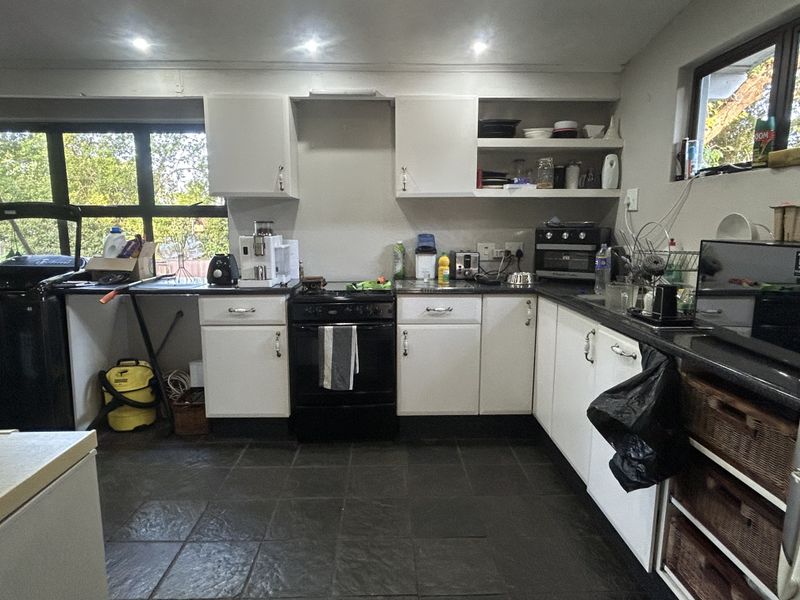 Functional kitchen featuring dark stone countertops, white cabinetry, tiled flooring, and recessed lighting, offering a practical layout with ample storage space.