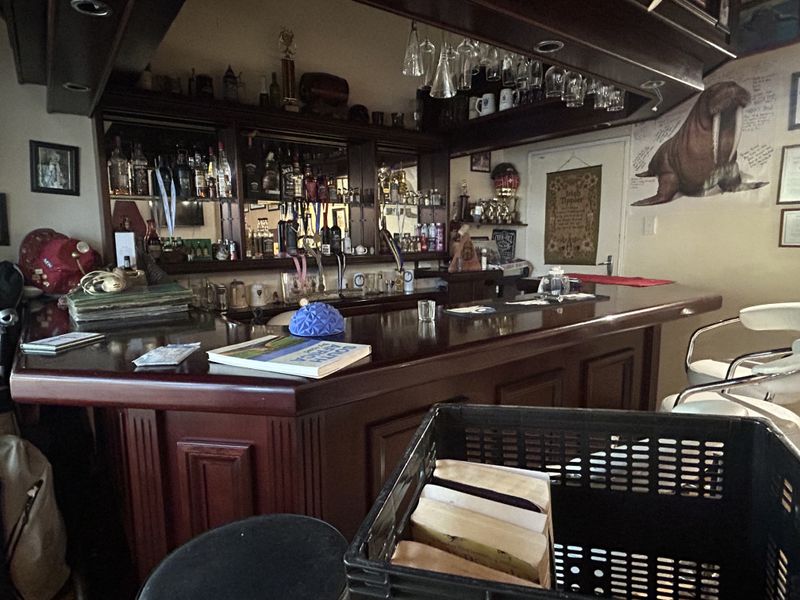 A dedicated home bar area featuring a substantial timber counter, mirrored back bar shelving, and integrated overhead glass storage.