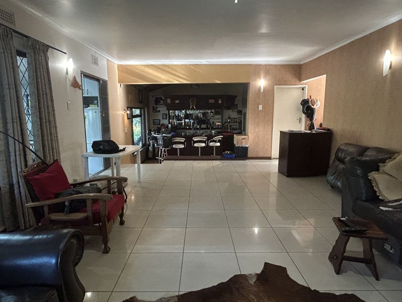 Spacious open-plan living area featuring large floor tiles and a dedicated built-in bar area, offering a versatile layout for entertaining.