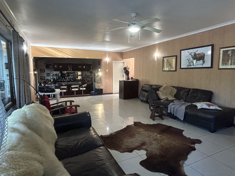 Spacious open-plan living area featuring tiled flooring, a ceiling fan, and a dedicated built-in bar area for entertaining.