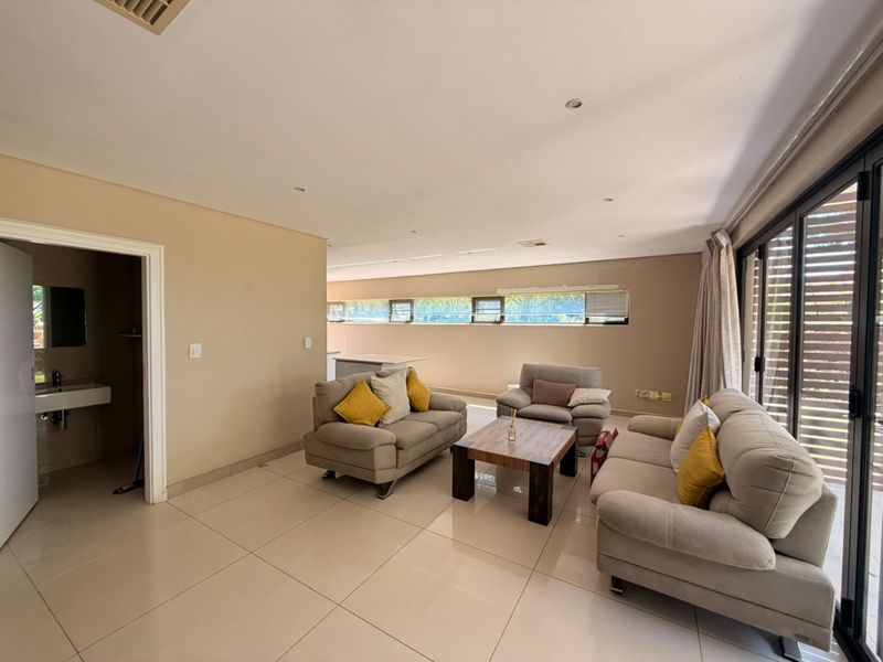Spacious open-plan living area featuring neutral tiled flooring, recessed lighting, and large sliding glass doors providing access to the exterior.