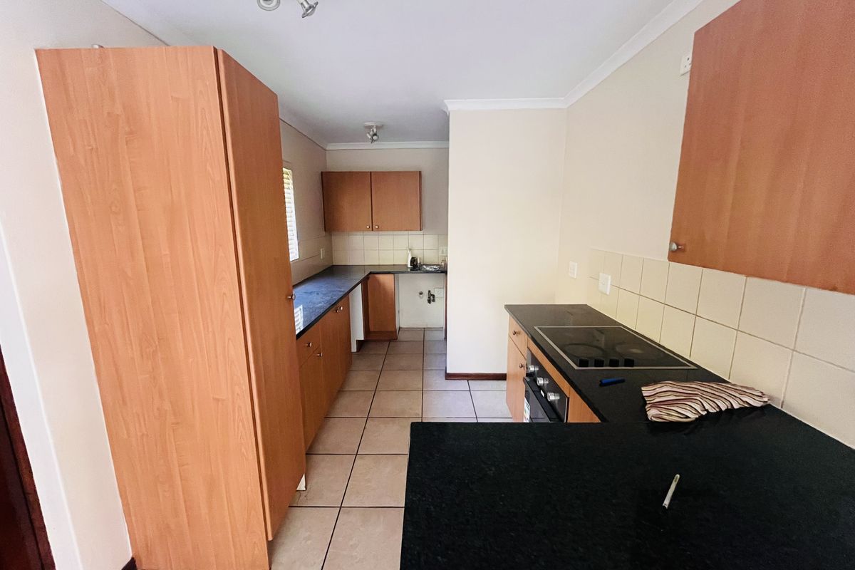 A functional kitchen featuring laminate cabinetry, granite countertops, tiled backsplash, and built-in cooking appliances with ceramic tile flooring.