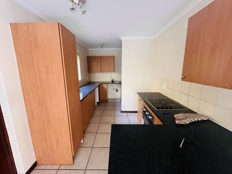 A functional kitchen featuring laminate cabinetry, granite countertops, tiled backsplash, and built-in cooking appliances with ceramic tile flooring.