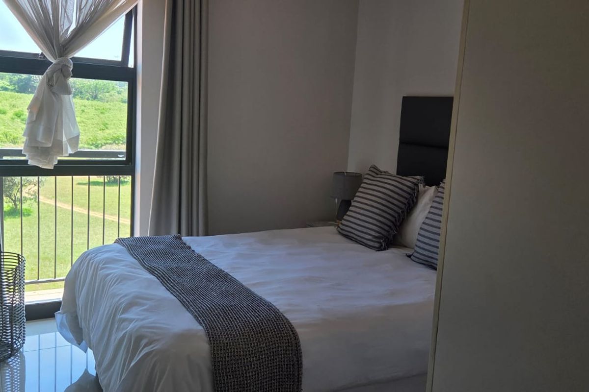 A well-lit bedroom featuring tiled flooring and a large window with access to an outdoor view.