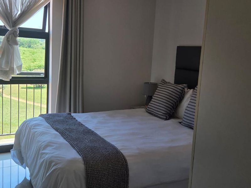 A well-lit bedroom featuring tiled flooring and a large window with access to an outdoor view.