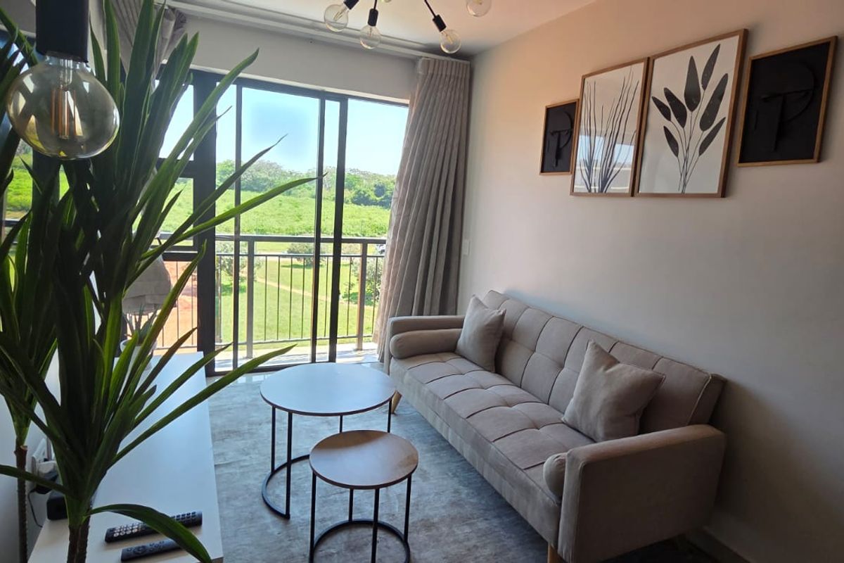 A bright living room featuring a large sliding glass door that opens to a balcony with scenic green views.