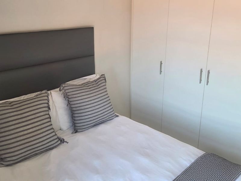 A well-maintained bedroom featuring a built-in wardrobe with clean white finishes and neutral wall tones.