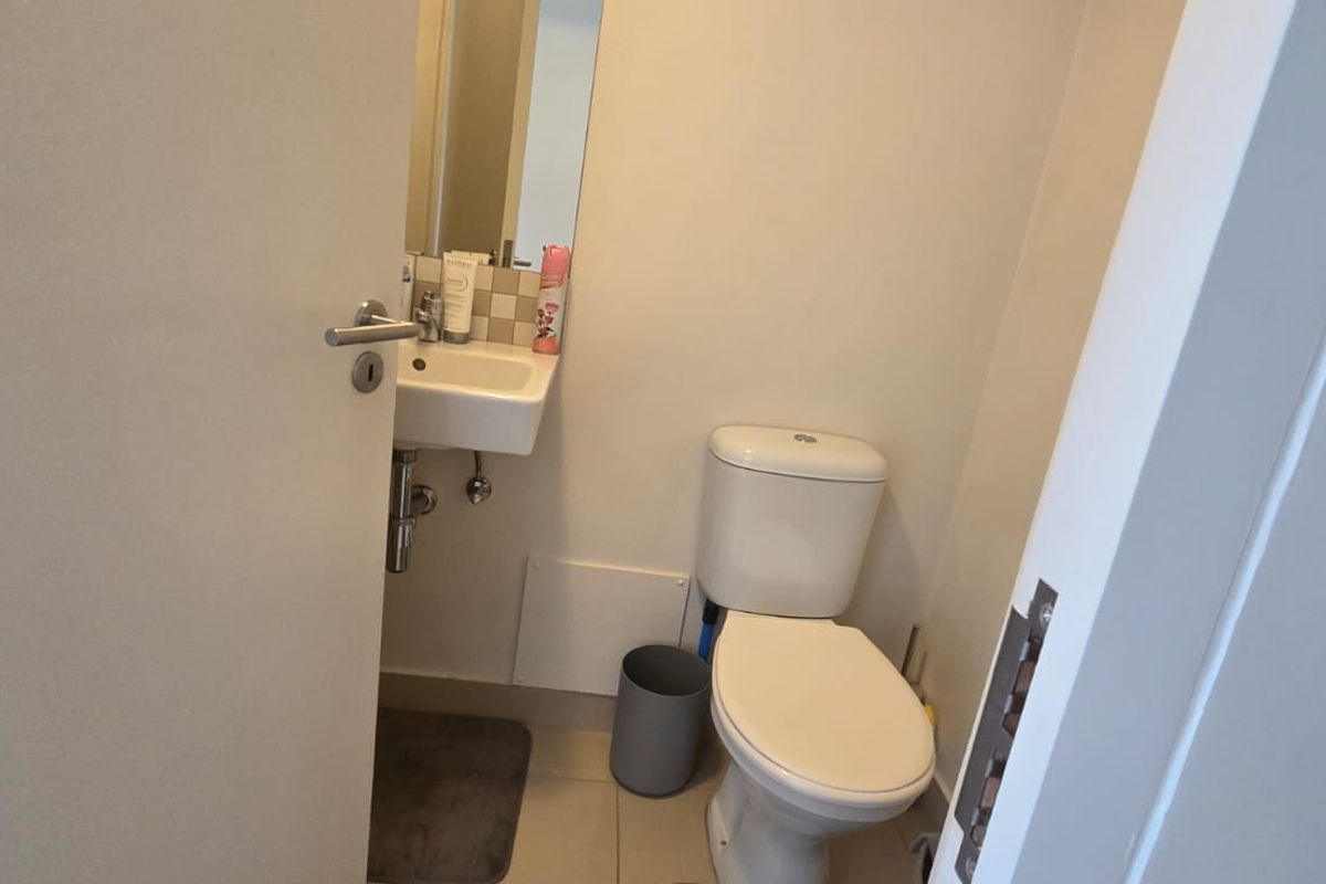 A compact guest bathroom featuring a wall-mounted basin, toilet, and tiled splashback.