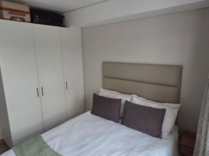 A well-maintained bedroom featuring a neutral color palette and a functional built-in wardrobe for storage.