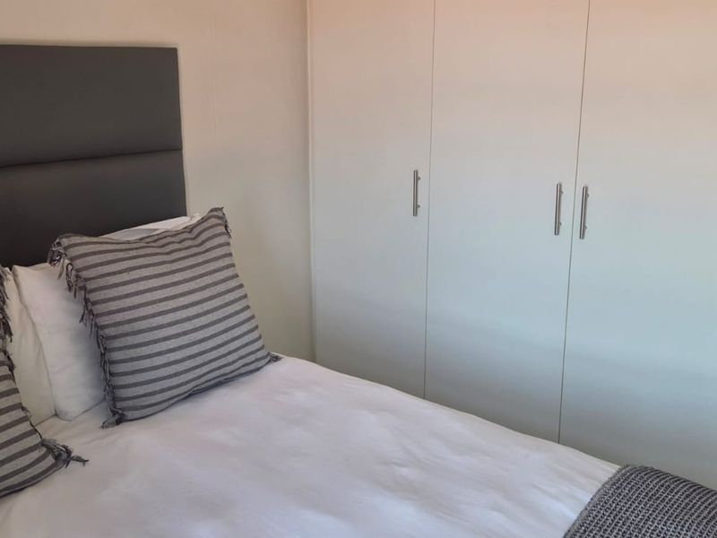 A well-maintained bedroom featuring built-in cupboards and neutral tiled flooring, offering a clean and functional living space.