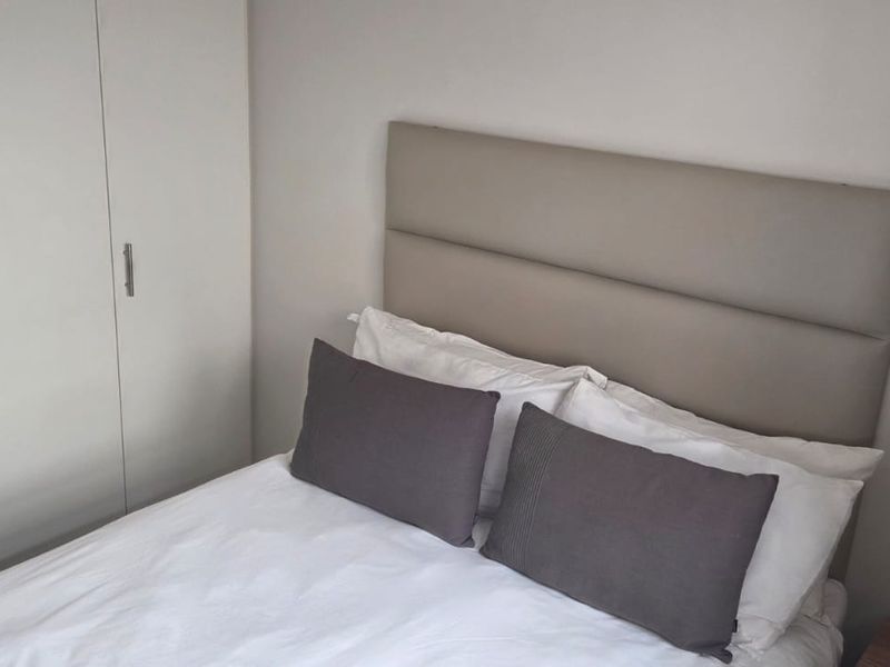 A cozy bedroom featuring a neutral color palette and a functional built-in wardrobe for efficient storage.