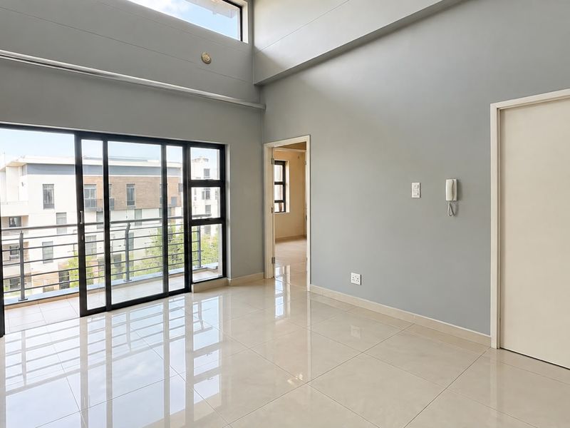Spacious, light-filled living area featuring high ceilings, large sliding glass doors leading to a balcony, and modern tiled flooring.