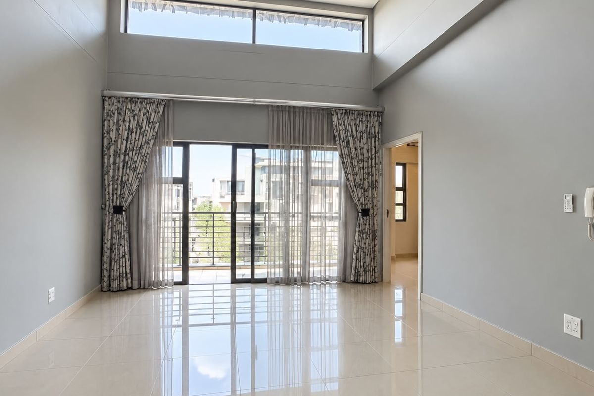 Spacious living area featuring double volume ceilings, clerestory windows, and large sliding doors leading to a balcony with polished porcelain tile flooring.