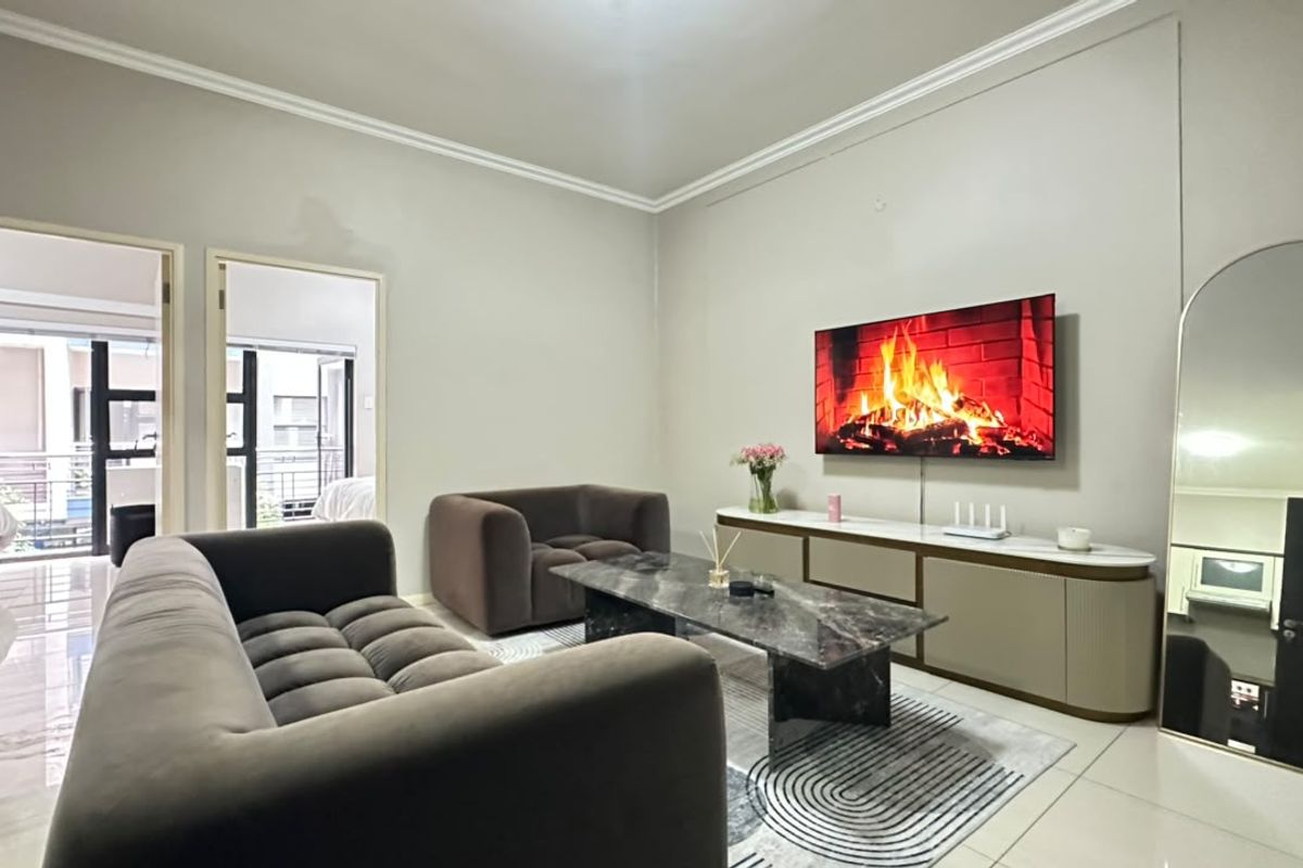 A well-maintained living room featuring neutral wall tones, crown molding, and polished tile flooring, providing a clean and contemporary living space.
