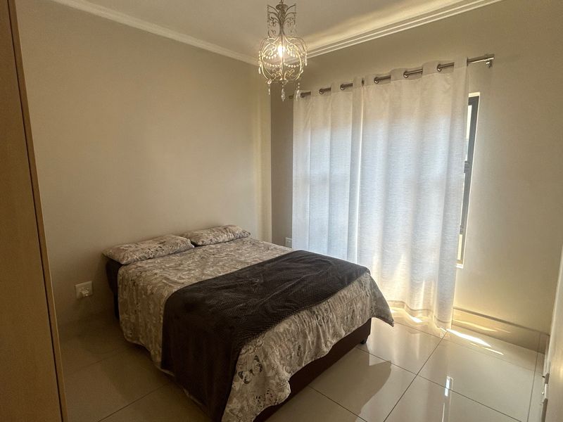 A well-maintained bedroom featuring tiled flooring, a built-in cupboard, and natural light through a window with curtaining.