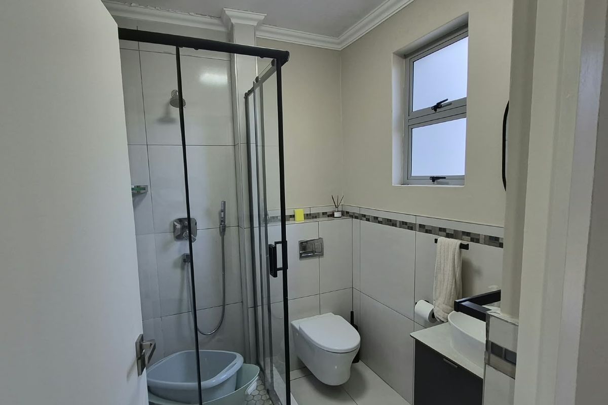 A modern, well-maintained bathroom featuring a glass-enclosed shower, wall-mounted toilet, and a sleek vanity with a vessel sink.