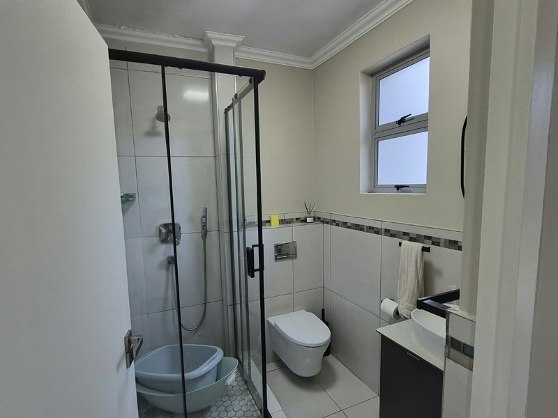 A modern, well-maintained bathroom featuring a glass-enclosed shower, wall-mounted toilet, and a sleek vanity with a vessel sink.