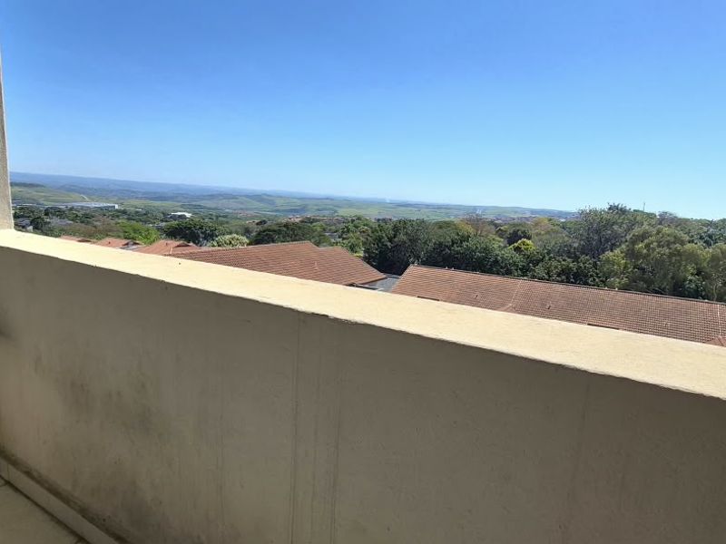 A balcony featuring tiled flooring and a solid masonry balustrade, offering expansive elevated views of the surrounding landscape and neighborhood.
