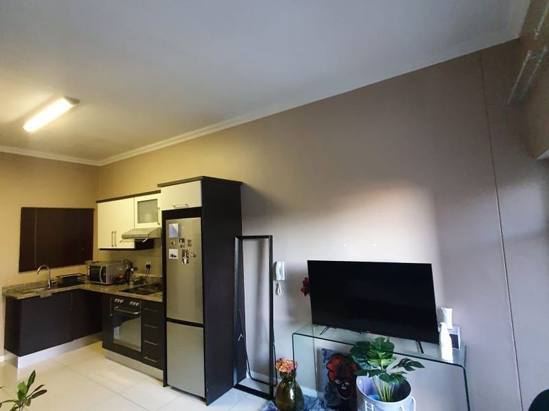 Open-plan living area featuring a compact kitchen with built-in cabinetry, granite countertops, and tiled flooring throughout.