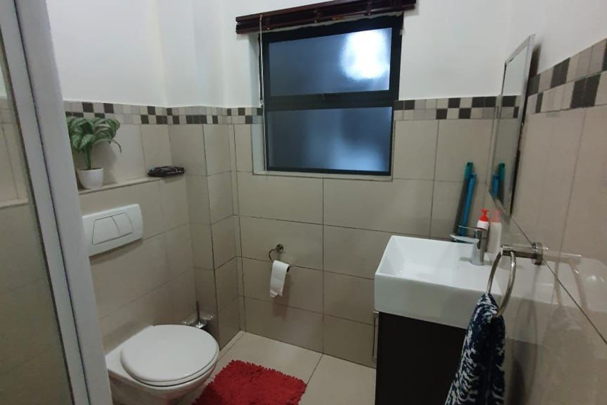 A modern bathroom featuring a wall-hung toilet, a sleek wall-mounted vanity with basin, and neutral tiled finishes throughout.
