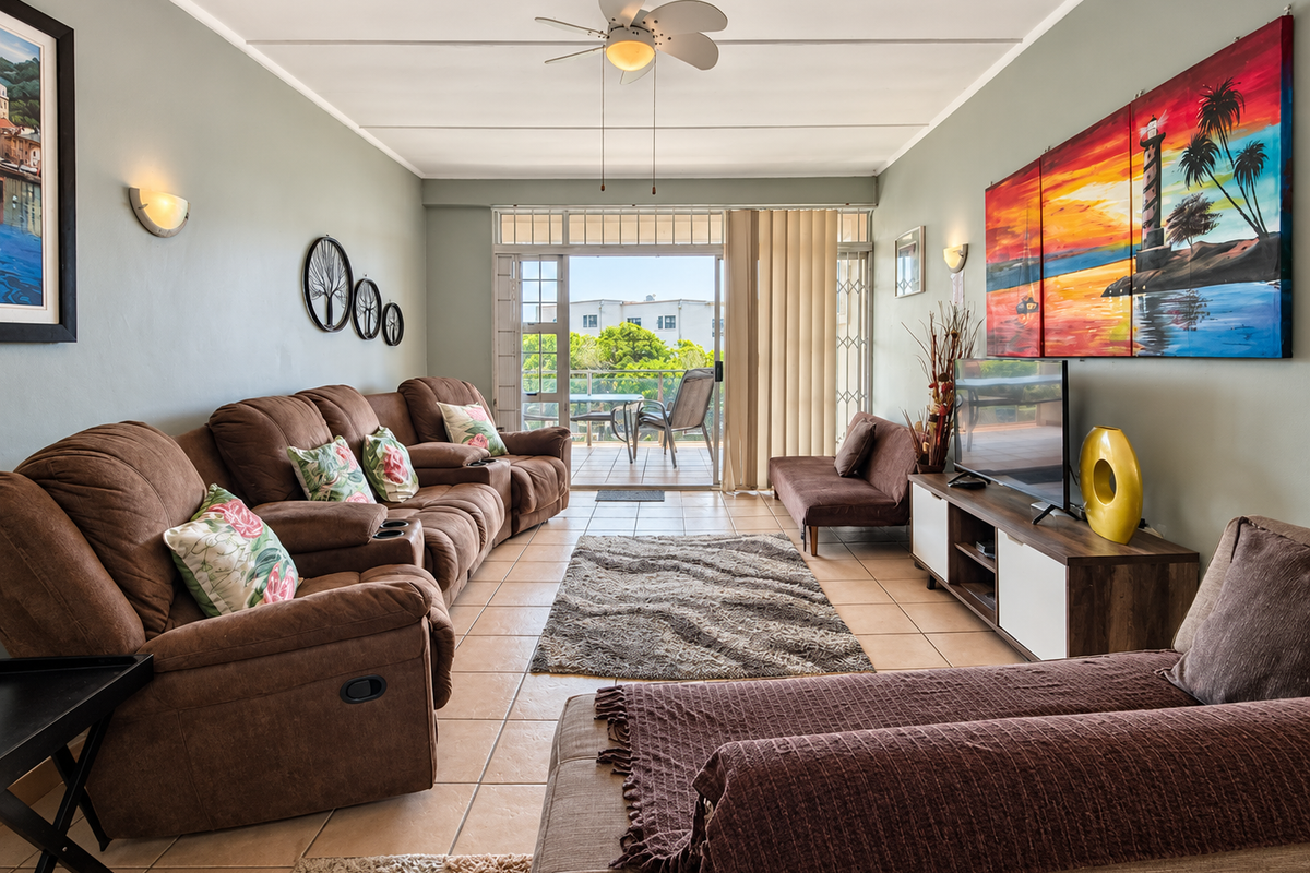 A comfortable living room featuring tiled flooring, a ceiling fan, and a sliding glass door that opens onto a balcony.