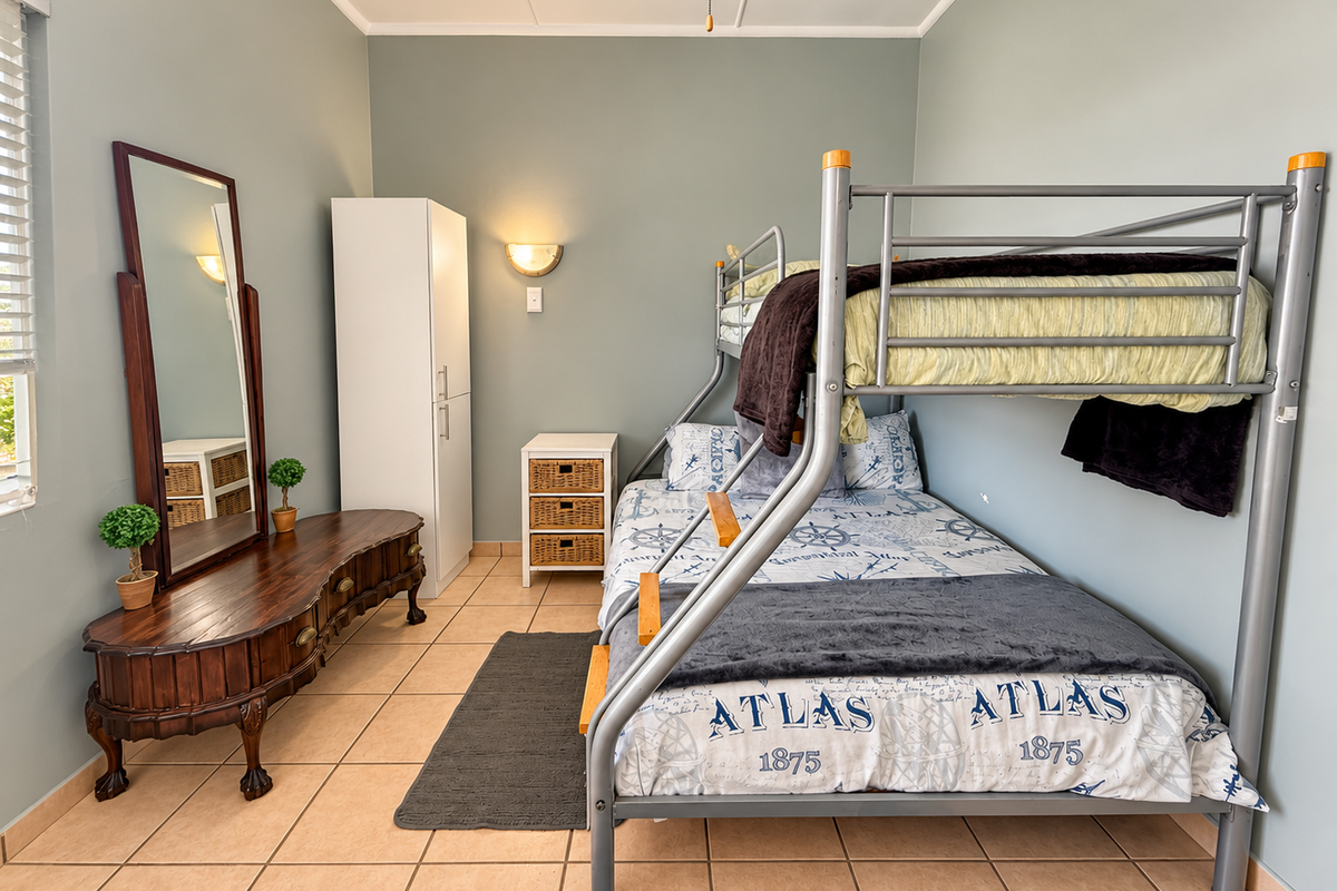 A well-maintained bedroom featuring tiled flooring, a built-in wardrobe, and a wall-mounted light fixture, providing a functional and comfortable living space.