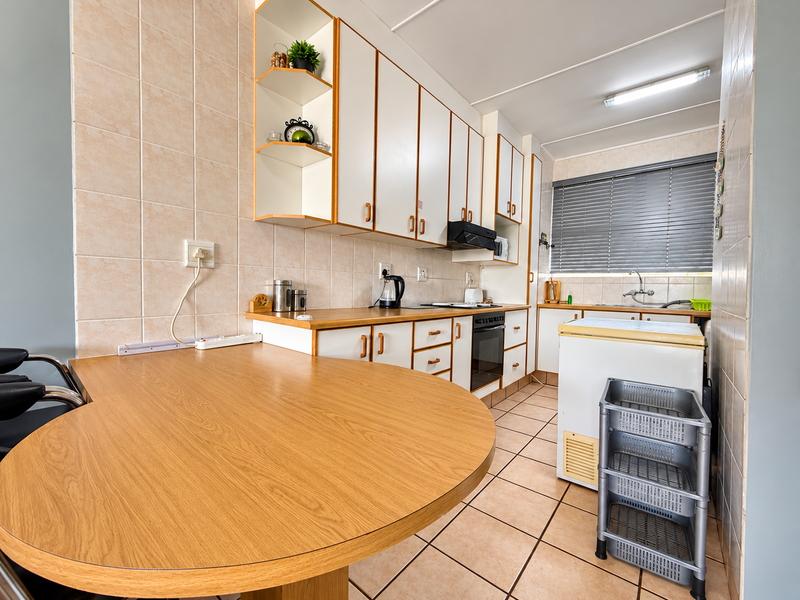 A functional kitchen featuring built-in cabinetry, laminate countertops, a built-in oven, and ceramic tile finishes throughout.