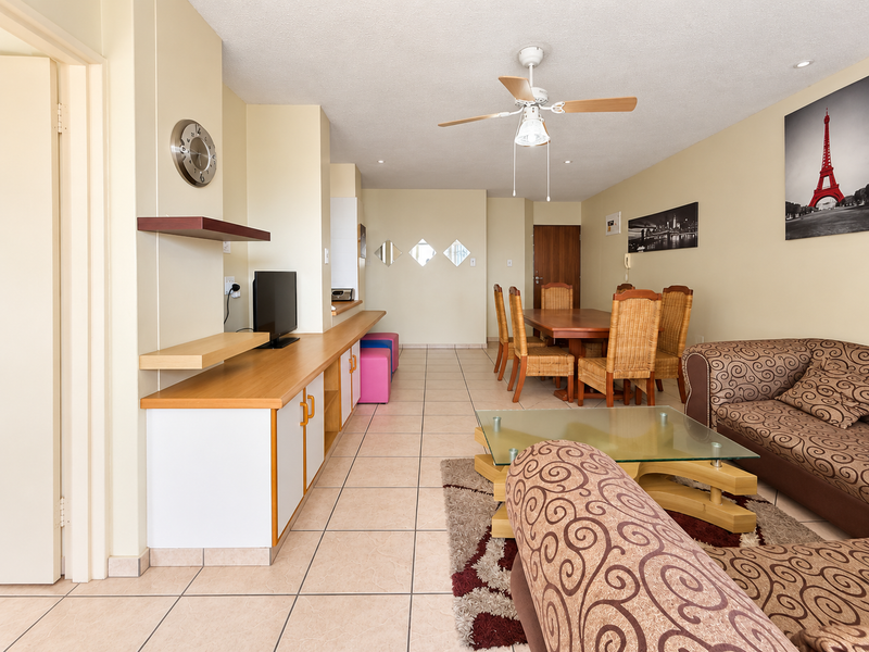 Open-plan living and dining area featuring tiled flooring, a ceiling fan, and built-in cabinetry, offering a functional layout for daily living.