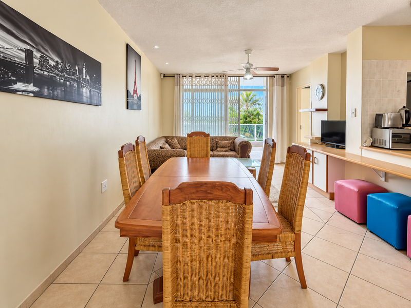 Open plan living and dining area featuring tiled floors, a ceiling fan, and direct access to a balcony through sliding glass doors.