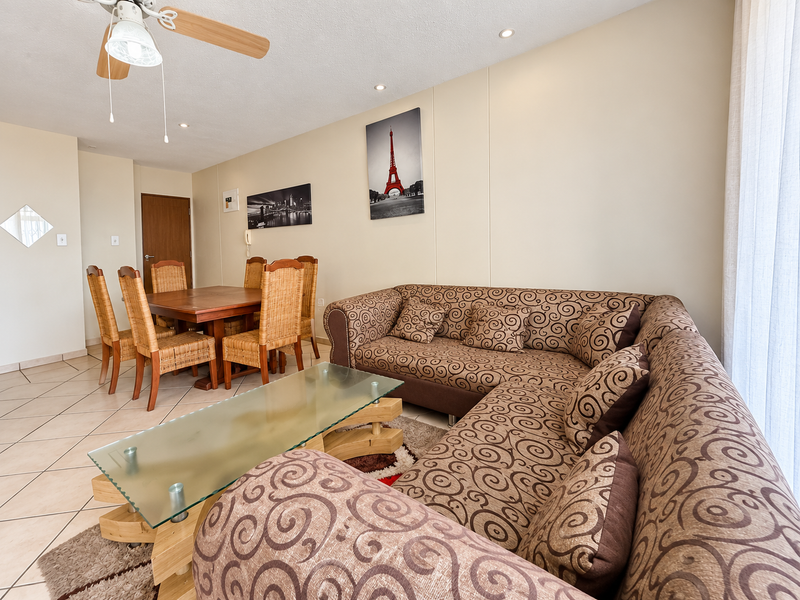 An open-plan living and dining area featuring tiled flooring, recessed lighting, and a ceiling fan, offering a functional layout for daily living.