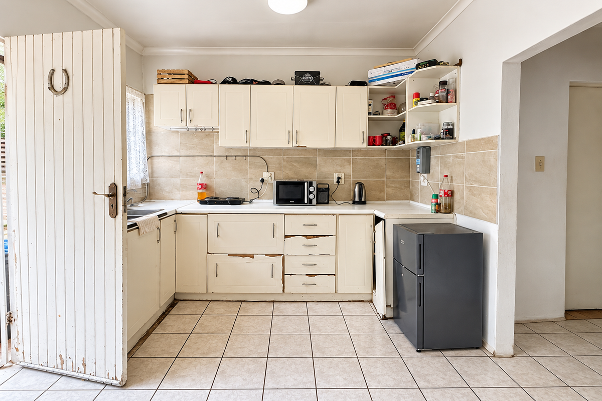 A functional kitchen featuring tiled flooring, a tiled backsplash, and built-in cabinetry, currently showing signs of wear and requiring cosmetic updates.