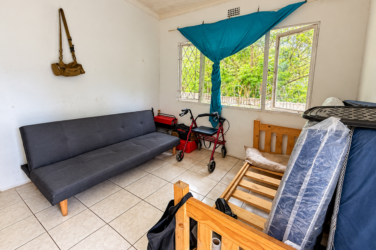 A living area featuring tiled flooring and steel-framed windows with security bars, requiring cosmetic updates to improve the overall aesthetic.