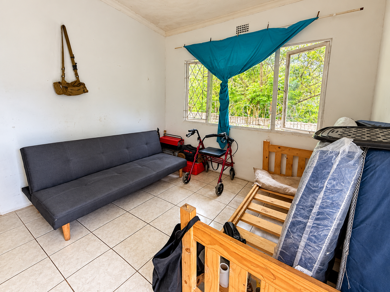 A living area featuring tiled flooring and steel-framed windows with security bars, requiring cosmetic updates to improve the overall aesthetic.
