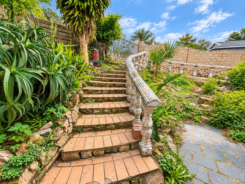 Outdoor garden area featuring a brick staircase with a decorative concrete balustrade, stone retaining walls, and established landscaping.
