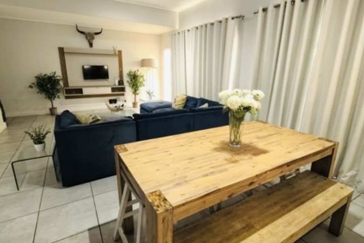 Spacious open-plan living and dining area featuring neutral tiled flooring, recessed lighting, and a modern built-in media console.